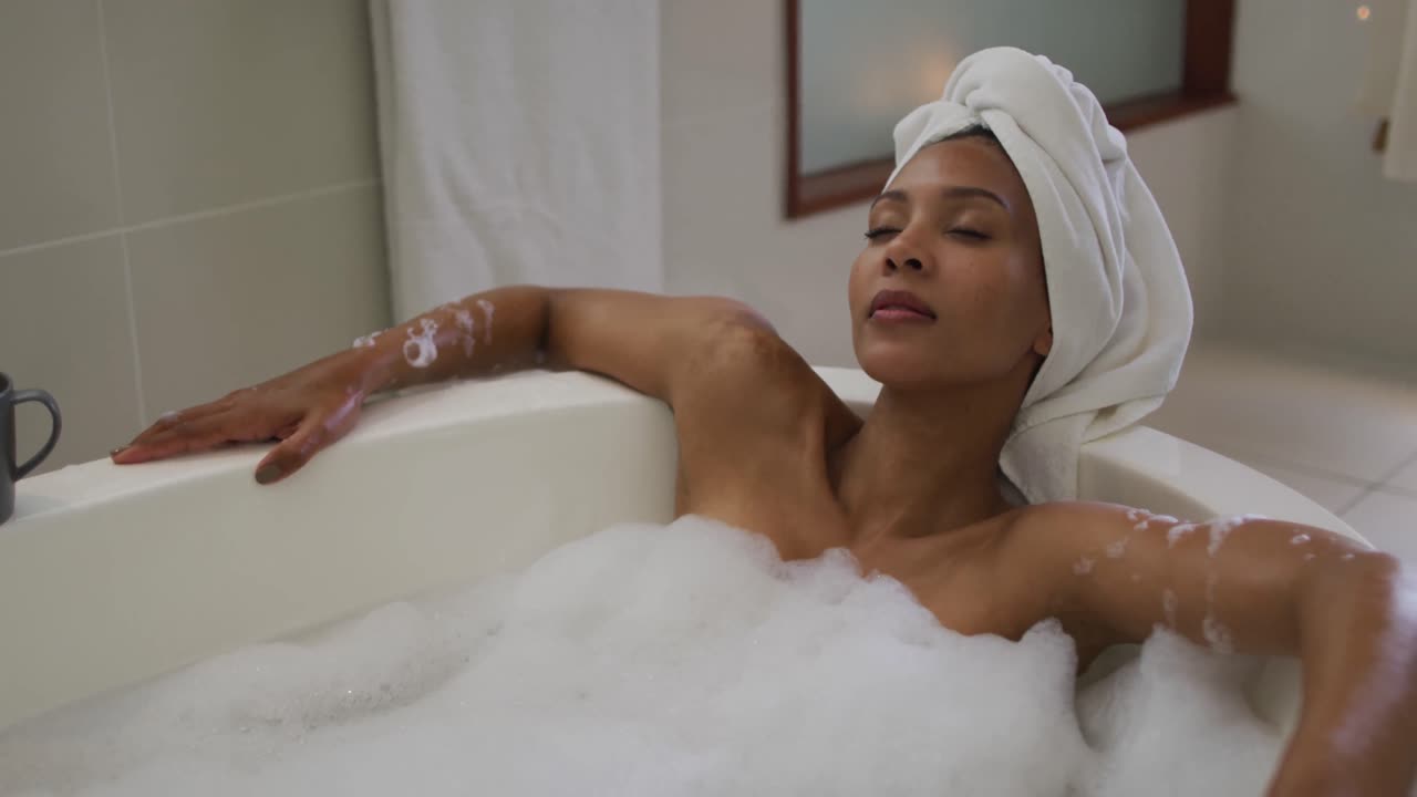 Mixed race woman wearing towel on head taking a bath