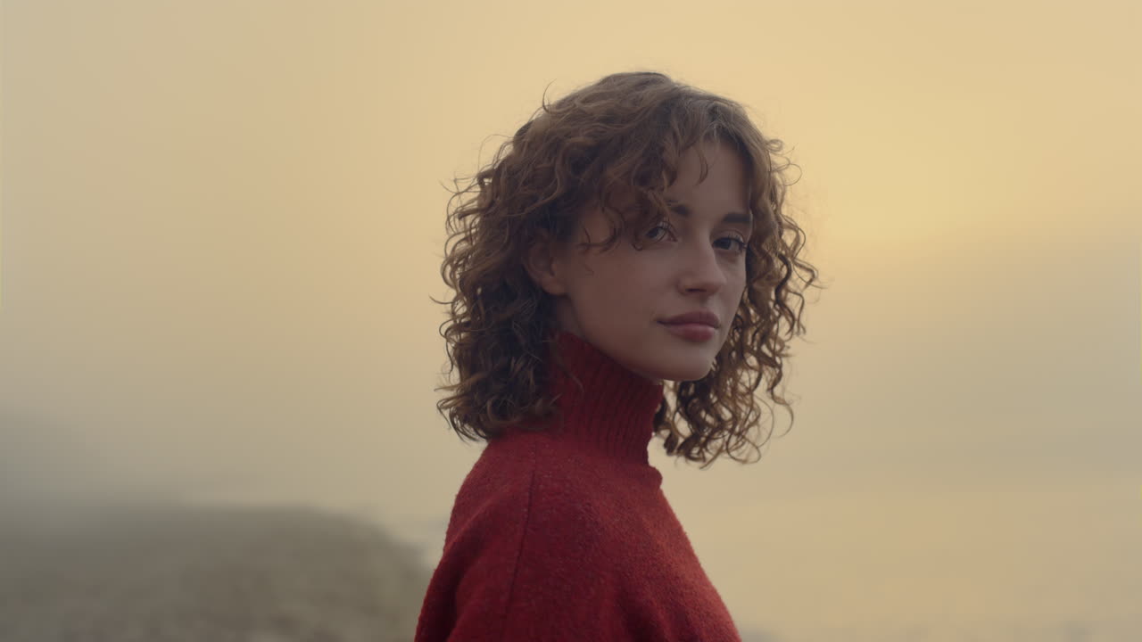 Donna sensuale in posa in spiaggia al mattino. Ragazza romantica che sorride alla telecamera.