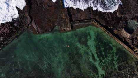 El-Hombre-Nada-En-La-Piscina-De-Mareas-Marinas-En-La-Costa-Rocosa