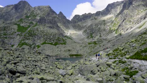 lago de montaña rocosa con hermosas vistas con excursionistas pasando en un día soleado