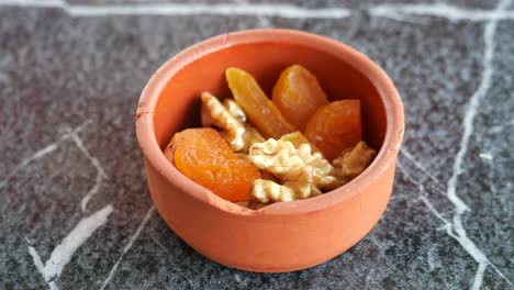 close up of walnuts and apricots in a clay bowl