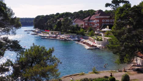 Aerial-reveal-shot-of-a-beach-resort-in-Mali-Losinj,-Croatia-on-a-bright-sunny-day