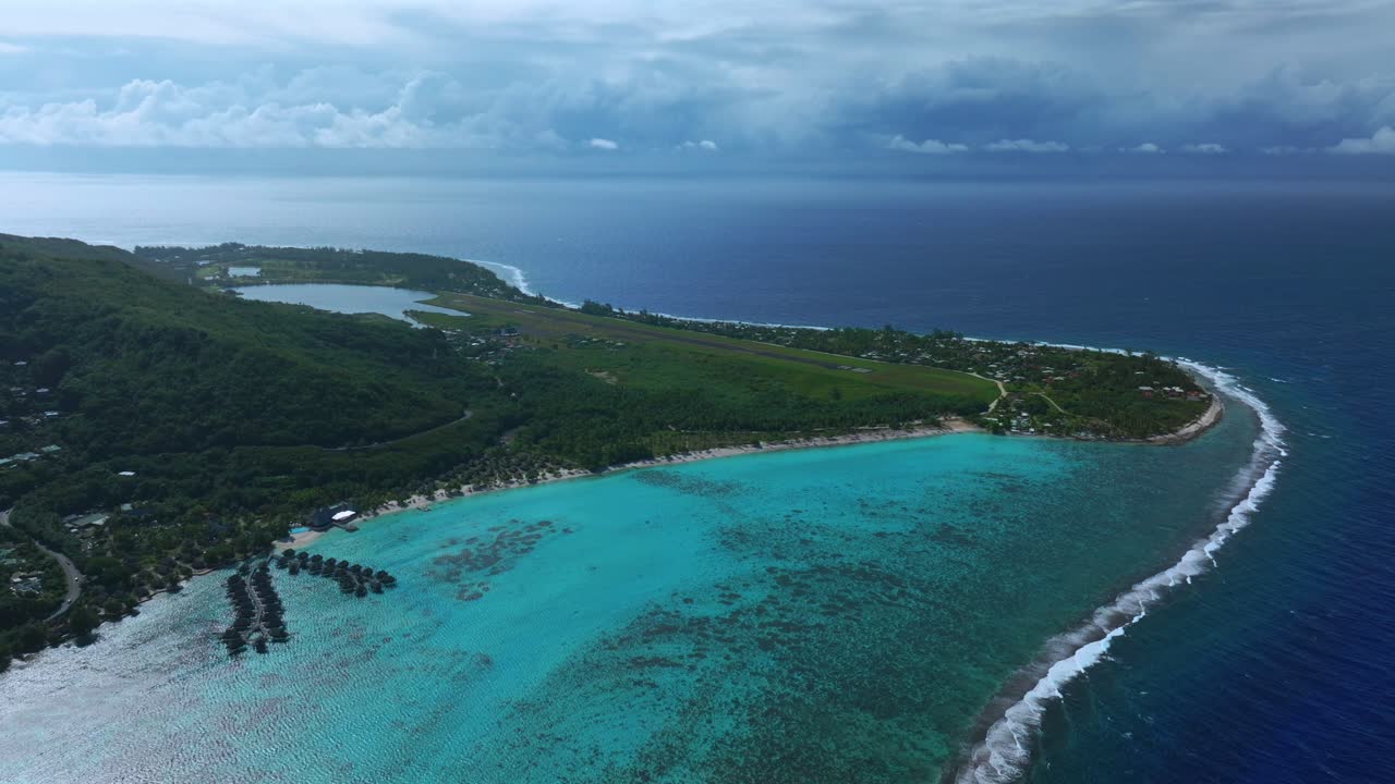 Luftdroneoptagelse af Stillehavet ved Moorea Temae Lufthavn, Opunohu Bugtens kystlinje, offentlige strande og bungalows i Fransk Polynesien, med et koralrev under en solrig morgen med blå himmel, skyer og turkis lagune.