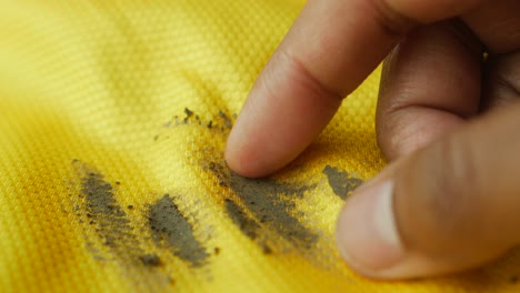 finger pointing to a stain on a yellow jersey