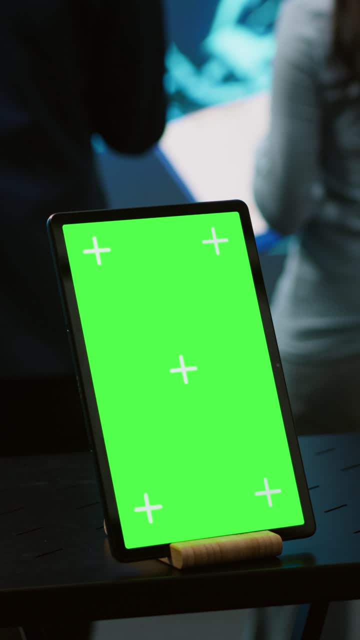 Video verticale. Tablet con schermo verde utilizzato da scienziati informatici in una startup di intelligenza artificiale.