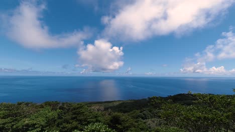 Lapso-De-Tiempo-De-Nubes-En-Movimiento-Rápido-Sobre-El-Océano-Azul-Abierto-Con-Reflejos-De-Nubes-En-El-Agua-Con-La-Isla-En-Primer-Plano