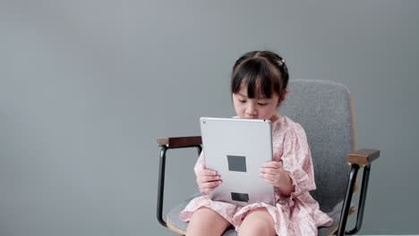 niño mirando una tableta digital y mirando una cámara alegre