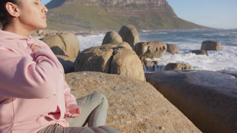 meditating on rocky beach, mature asian woman practicing mindfulness and relaxation, copy space