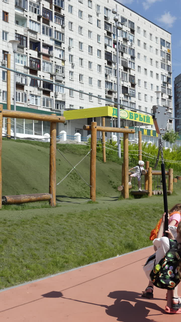 дети наслаждаются цип-линией на игровой площадке возле квартир