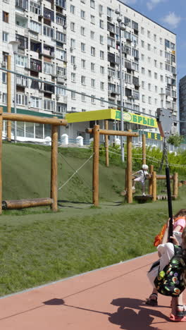 niños disfrutando de una tirolesa en un patio de recreo cerca de apartamentos