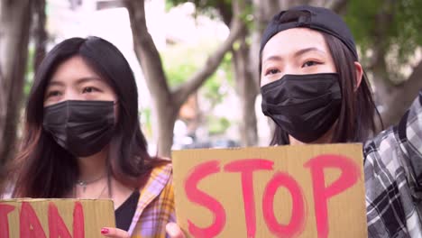 mujeres asiáticas con carteles durante una protesta en la ciudad