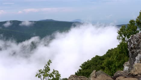 Handheld-shot-of-low-clouds-swirling-around-forested-hills