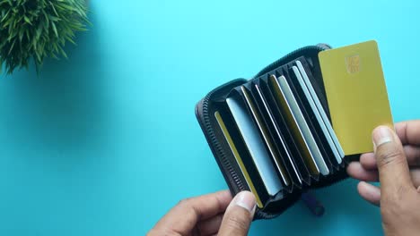 close-up of a man holding a black leather wallet with multiple credit cards inside