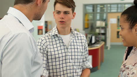 teacher talking with college students in library