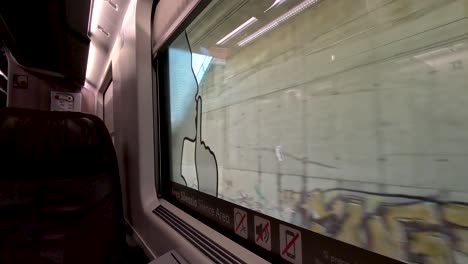 a view looking out of the window of a train travelling on the outskirts of a city in an empty frecciarossa business class carriage, italy