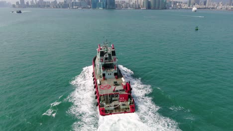 Small-Offshore-supply-ship-roaring-across-Hong-Kong-bay,-Aerial-view