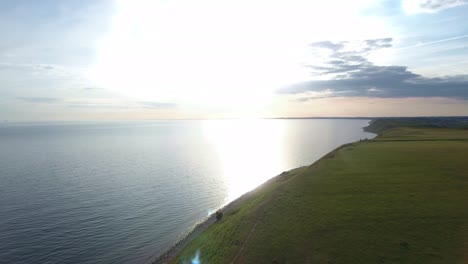 the baltic sea from the steep hill of ales stenar by sunset in south sweden skåne kåseberga, aerial forward slow