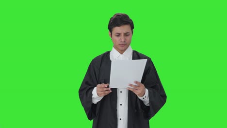 un abogado indio alegre leyendo contratos en pantalla verde.