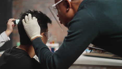 African-American-biologist-examines-man-hair-and-head-skin