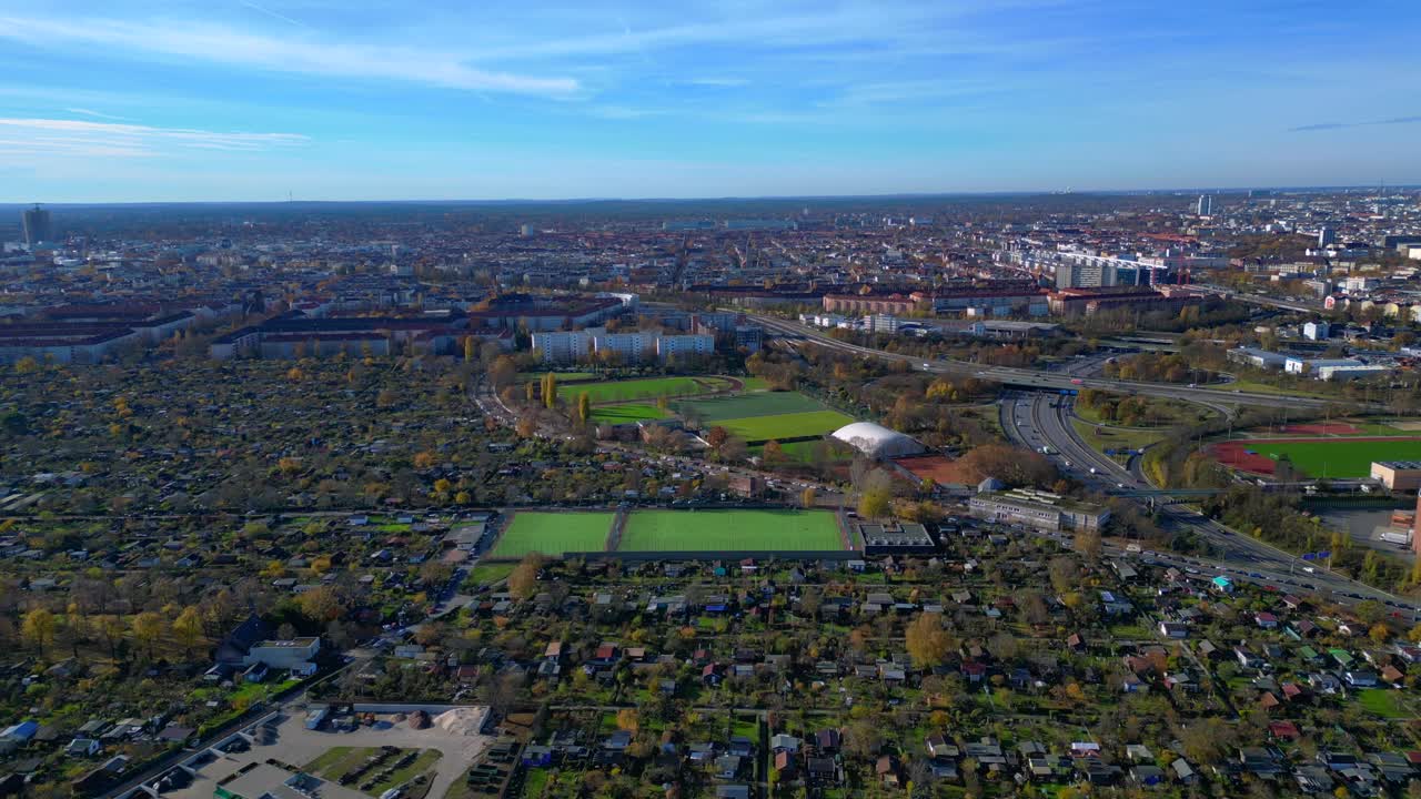 Berlin urban landscape with a large allotment garden area, sports soccer fields, football pitches and city infrastructure. panorama overview drone