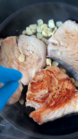 cooking tuna steaks with garlic in a pan