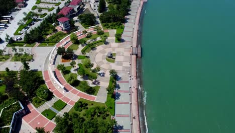 Aerial-tour-over-Xingfu-seaside-park-with-cityscape-and-high-speed-boat-in-background-in-Weihai,-China