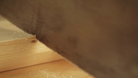 Eine-Makroaufnahme-Eines-Tischlers,-Der-In-Einer-Möbelwerkstatt-In-Zeitlupe-Ein-Stück-Holz-Mit-Einer-Zapfensäge-Schneidet