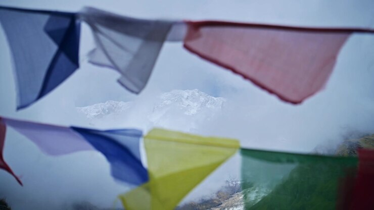 Bedeflag i sneklædte bjerge i Nepal, nærbillede af farverige tibetanske bedeflag i tåge i Himalaya, der blæser i vinden i Annapurna, farverigt religiøst symbol på buddhisme i naturen.