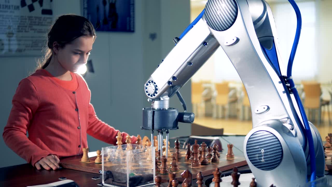 Little smart girl and robotic arm playing chess at school.
