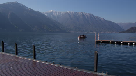 boat leaving marina by the lake como in summer in tremezzo, lombardy, italy, wide shot