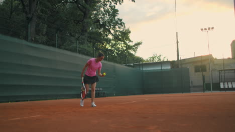 slow-motion-side-view-of-a-young-athlete-trains-the-serve-of-the-tennis-ball.-A-teenage-athlete-is-playing-tennis-on-a-court.-An-active-girl-is-powerfully-hitting-a-ball-during-sport-practicing