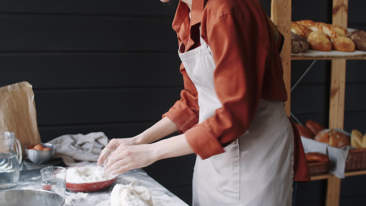 Female Baker Kneading Dough in Kitchen