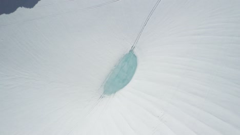 aerial top down of a man skiing down a snow capped slope at perito moreno hill, el bolsón, patagonia argentina