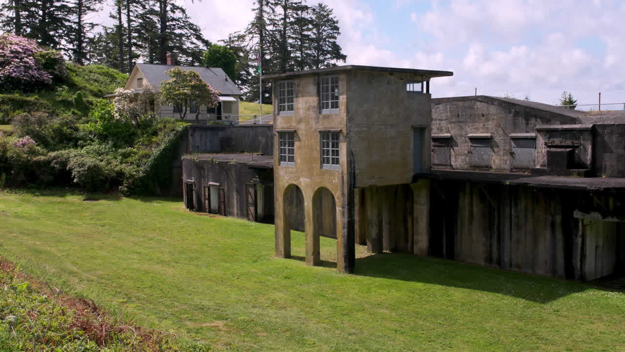 Edifícios militares históricos localizados em uma encosta gramada no Forte Columbia com vista para o Rio Columbia