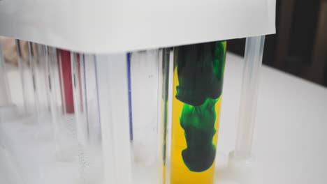 flow of dark green paint settles down in test tube macro