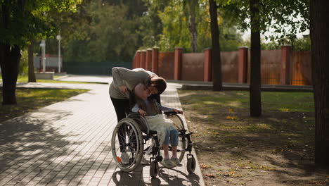 redhead woman leans to kiss cheek of daughter in wheelchair