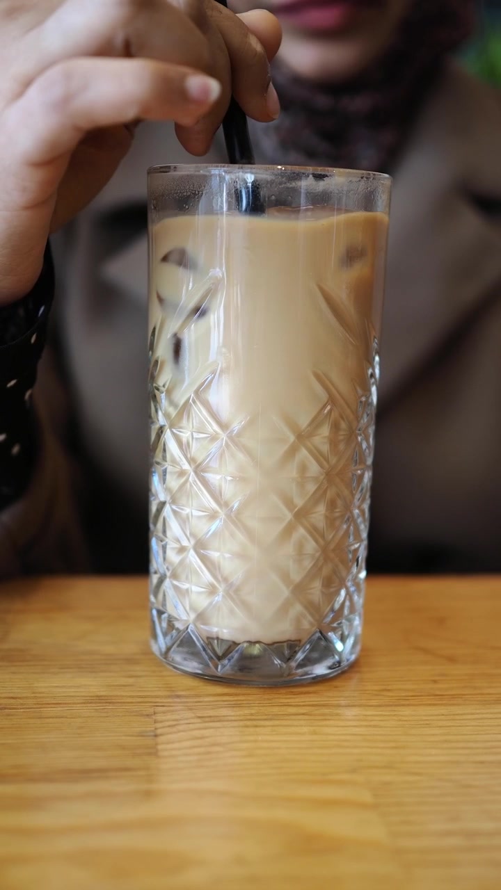 Donna che mescola caffè freddo in un bicchiere in un bar