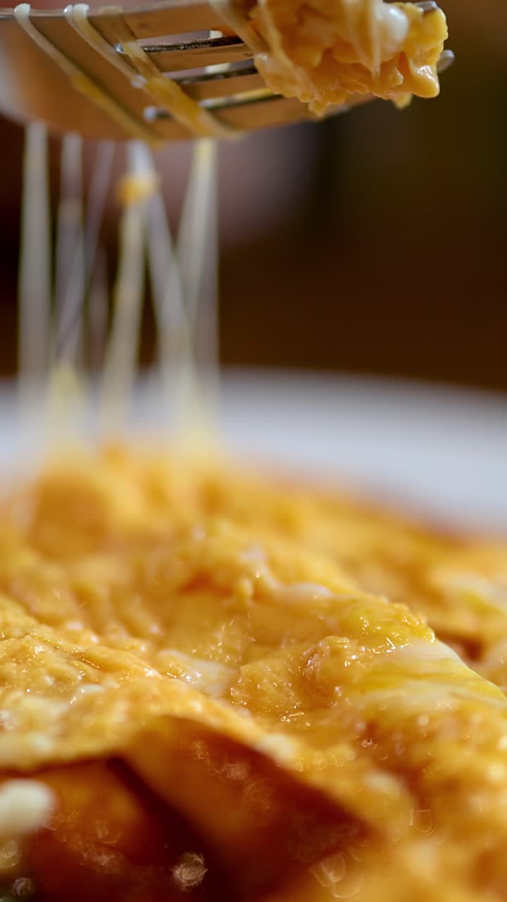 Detailní záběr sýrových enchilad s táhnoucím se rozpuštěným sýrem