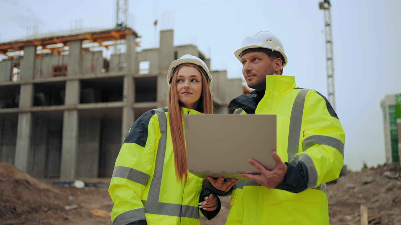 dos ingenieros civiles están discutiendo el proyecto y el progreso de la construcción de un edificio moderno al aire libre hombre y mujer
