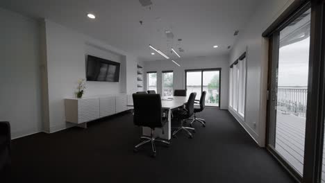 wide push-in shot of a conference room with a white table, black chairs, and natural light