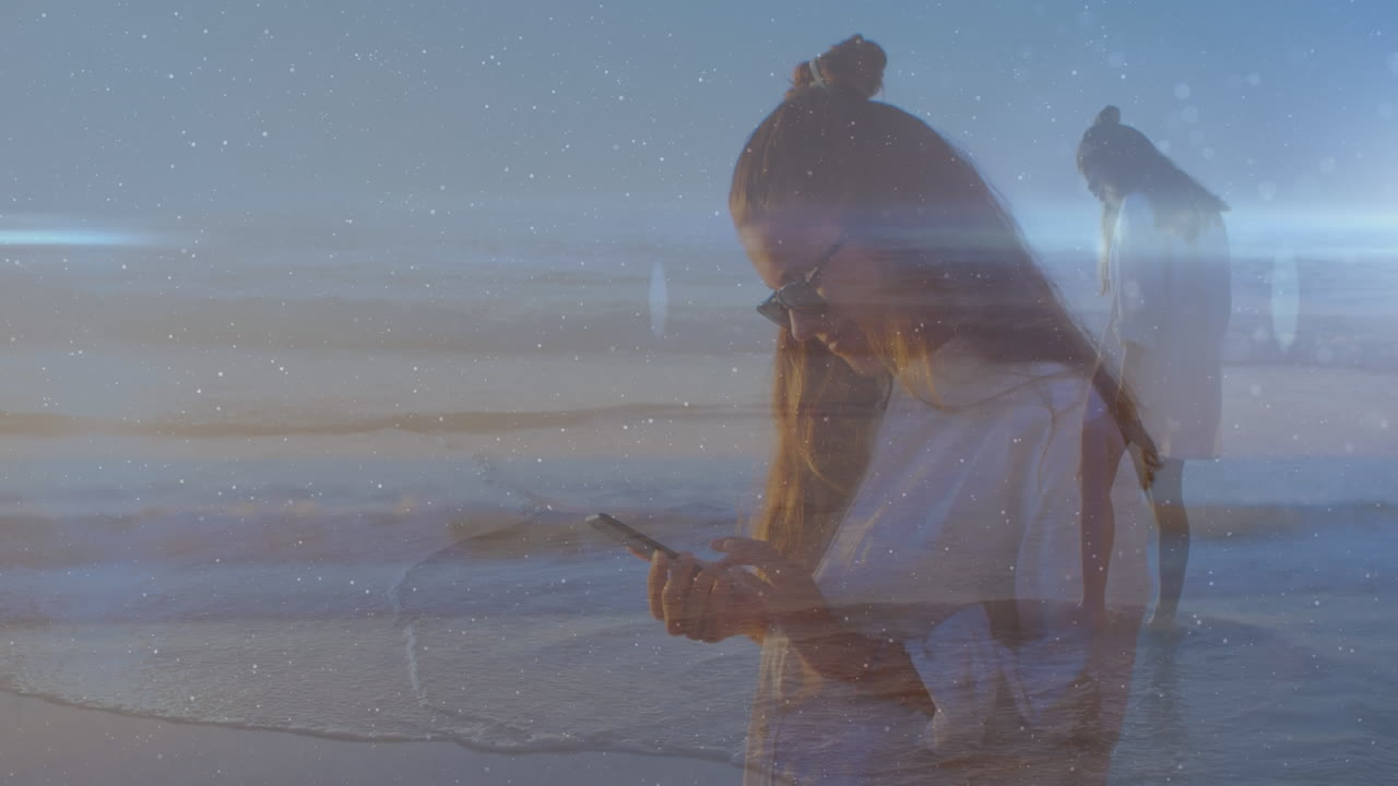 해변에서 스마트 폰을 사용하는 두 인종의 여성 위에 빛의 트레일의 애니메이션