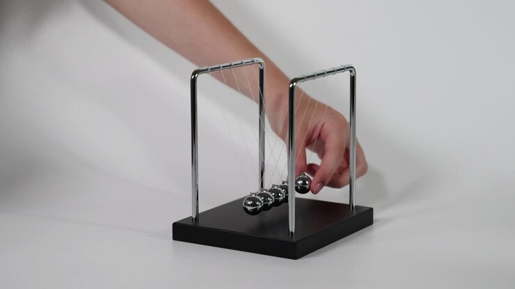 Hand initiates motion of Newton's Cradle