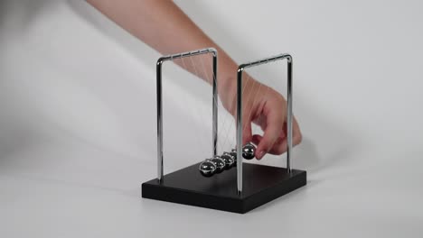 hand initiates motion of newton's cradle