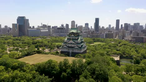 un avión girando alrededor del histórico castillo de osaka con parque, foso, rascacielos y ciudad urbana en osaka, japón