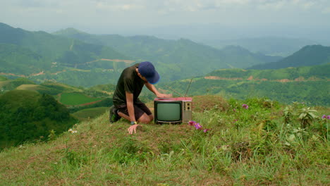 young man taps on the top of a cathode-ray tube television to get it to work after reception goes out