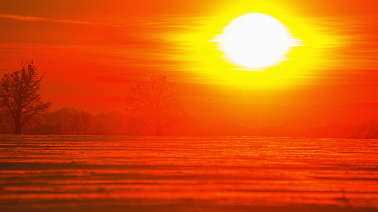 orange and reddish sunset reflects and illuminates wild countryside meadow. Timelapse shot