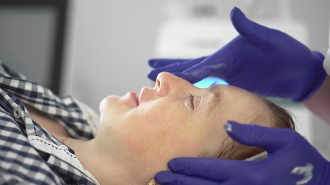 Cosmetologist smoothes wrinkles with microcurrent. Hardware procedure in cosmetology. Peeling, phonophoresis, massage and facelift in a beauty clinic.