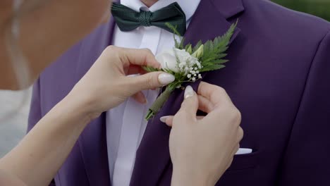 bride pinning a boutonniere on the groom before the wedding