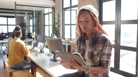 in modern office, diverse female team using tablets and computers collaborating on coding projects