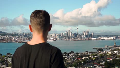 slowmo - young caucasian man looking at auckland skyline from devonport, new zealand